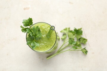 Healthy parsley smoothie in glass and leaves on light textured table, flat lay