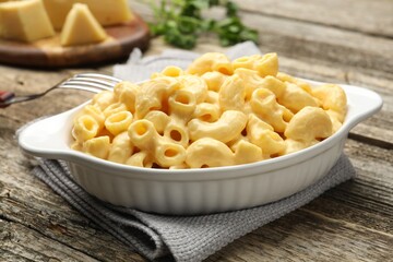 Delicious pasta with cheese sauce and fork on wooden table, closeup