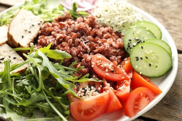 Delicious salad with brown rice on wooden table, closeup