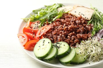 Delicious salad with brown rice on white wooden table, closeup