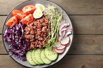 Tasty salad with brown rice on wooden table, top view