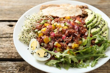Tasty salad with brown rice on wooden table, closeup