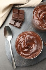 Tasty pudding and pieces of chocolate on grey table, flat lay