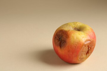 One rotten apple on beige background, closeup. Space for text
