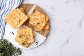Tasty salty crackers with thyme on white marble table, top view. Space for text
