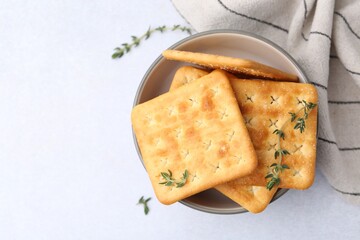 Tasty salty crackers with thyme on white table, top view. Space for text