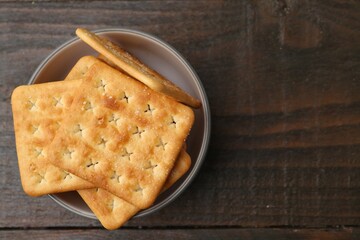 Tasty salty crackers on wooden table, top view. Space for text