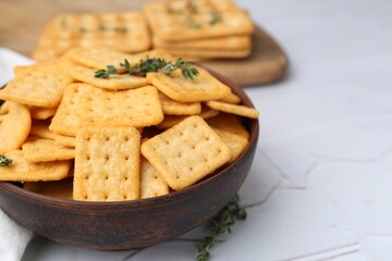 Tasty salty crackers and thyme on white textured table, closeup