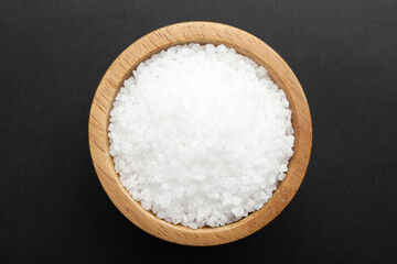 Salt in bowl on black background, top view