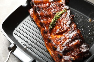 Delicious roasted pork ribs with rosemary on grey table, closeup
