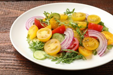 Fresh salad with yellow tomatoes on wooden table, closeup