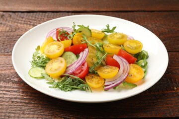 Fresh salad with yellow tomatoes on wooden table, closeup