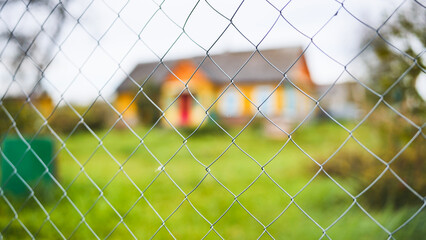 Chain link fence detail, blurring residential building behind, symbolizing boundary, privacy,...