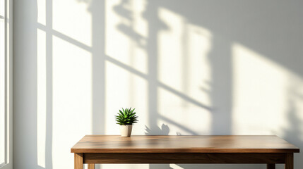 Fototapeta premium Sunlit interior with wooden table, potted plant, and shadow play