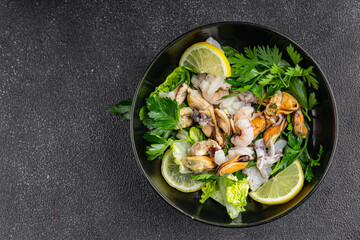 Seafood salad fruit de mer shrimp, mussels, squid, rapawn, prawn, green mixed leaf dish fresh food background on the table rustic food top view copy space keto paleo diet vegetarian pescetarian