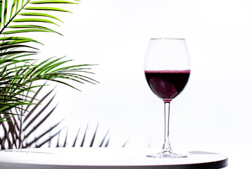 Non-alcoholic, alcohol free, red wine cabernet sauvignon in glass White background, palm leaves...