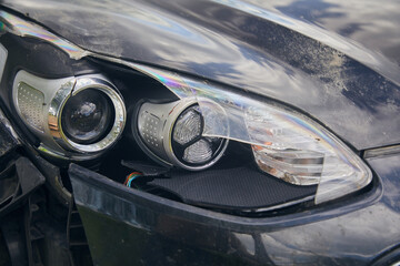 Broken headlight of a black car, close-up