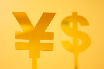 Two yellow currency symbols, the Chinese Yuan (¥) and Dollar ($), set against a bright yellow background