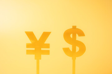 Two yellow currency symbols, the Chinese Yuan (¥) and Dollar ($), set against a bright yellow background