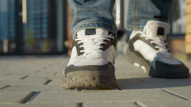 close up of cigarette being crushed under white and black sneaker as person stands on pavement during sunny day, symbolic act of quitting smoking with blurred urban background
