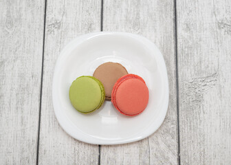 Color macarons lie on a plate. Delicious cookies on a plate on a light background