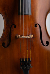 Detailed studio close-up of a classical cello showing the body and strings, photographed on a clean white background. The image highlights the fine wood grain, curved shape, and craftsmanship of the i