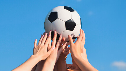 School friends holding soccer ball celebrating a victory under a blue sky, concept of teamwork and success