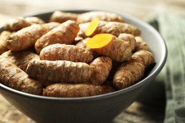 Tumeric rhizomes in bowl on table, closeup