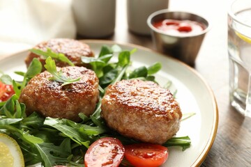 Delicious patties with greens, tomato, ketchup and drink on wooden table, closeup