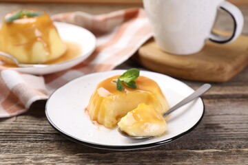 Delicious pudding with caramel sauce and mint served on wooden table
