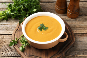 Delicious lentil cream soup with parsley on wooden table, closeup