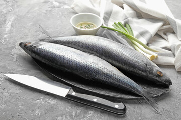 Salted herrings, spices and knife on grey table