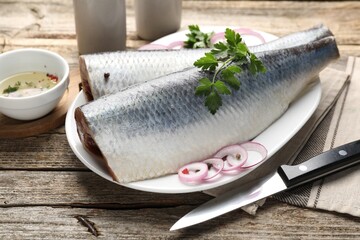 Tasty herring fillets with spices on wooden table, closeup