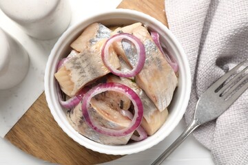 Pieces of delicious herring with onions on white table, top view