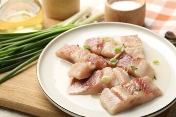 Pieces of delicious herring with green onions on table, closeup