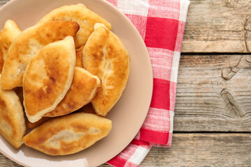 Delicious fried pyrizhky (stuffed pies) on wooden table, top view. Space for text