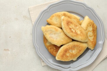 Delicious fried pyrizhky (stuffed pies) on light grey table, top view. Space for text