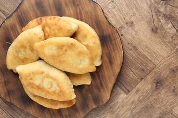 Delicious fried pyrizhky (stuffed pies) on wooden table, top view. Space for text