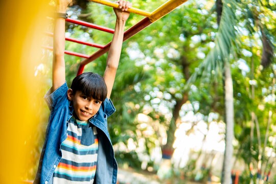 Happy child playing and having fun on monkey bars in playground