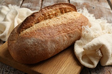 Fresh loaf of bread on wooden table, closeup