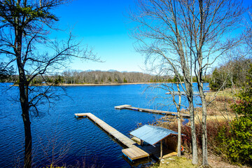 ready for summer cottage season:  lake in forest with finger docks extending from the shore line waiting for warmer weather shot in spring in ontario cottage country