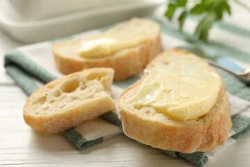 Slices of bread with butter on white wooden table, closeup