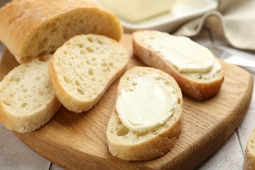 Pieces of bread with butter on light tiled table, closeup