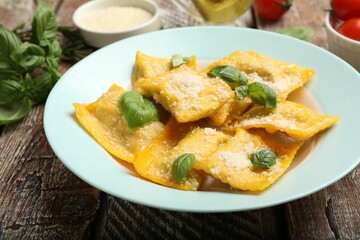 Delicious ravioli with cheese and basil on wooden table, closeup