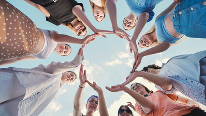 Obraz premium School friends unite in a circle against a bright blue sky, showcasing teamwork and friendship