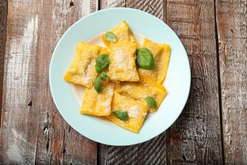 Delicious ravioli with cheese and basil on wooden table, top view