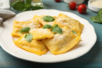 Delicious ravioli with cheese and basil on light blue wooden table, closeup