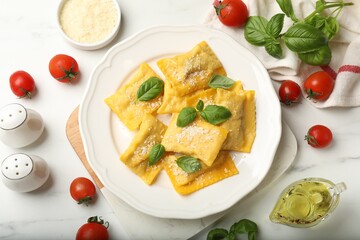 Delicious ravioli with cheese and basil served on white marble table, flat lay