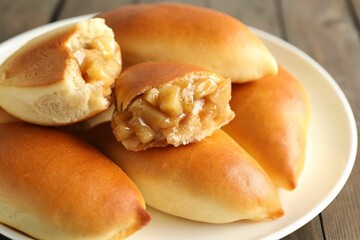 Tasty baked patties with apples on wooden table, closeup