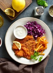 Schnitzel with potato fries, cabbage salad and sauce